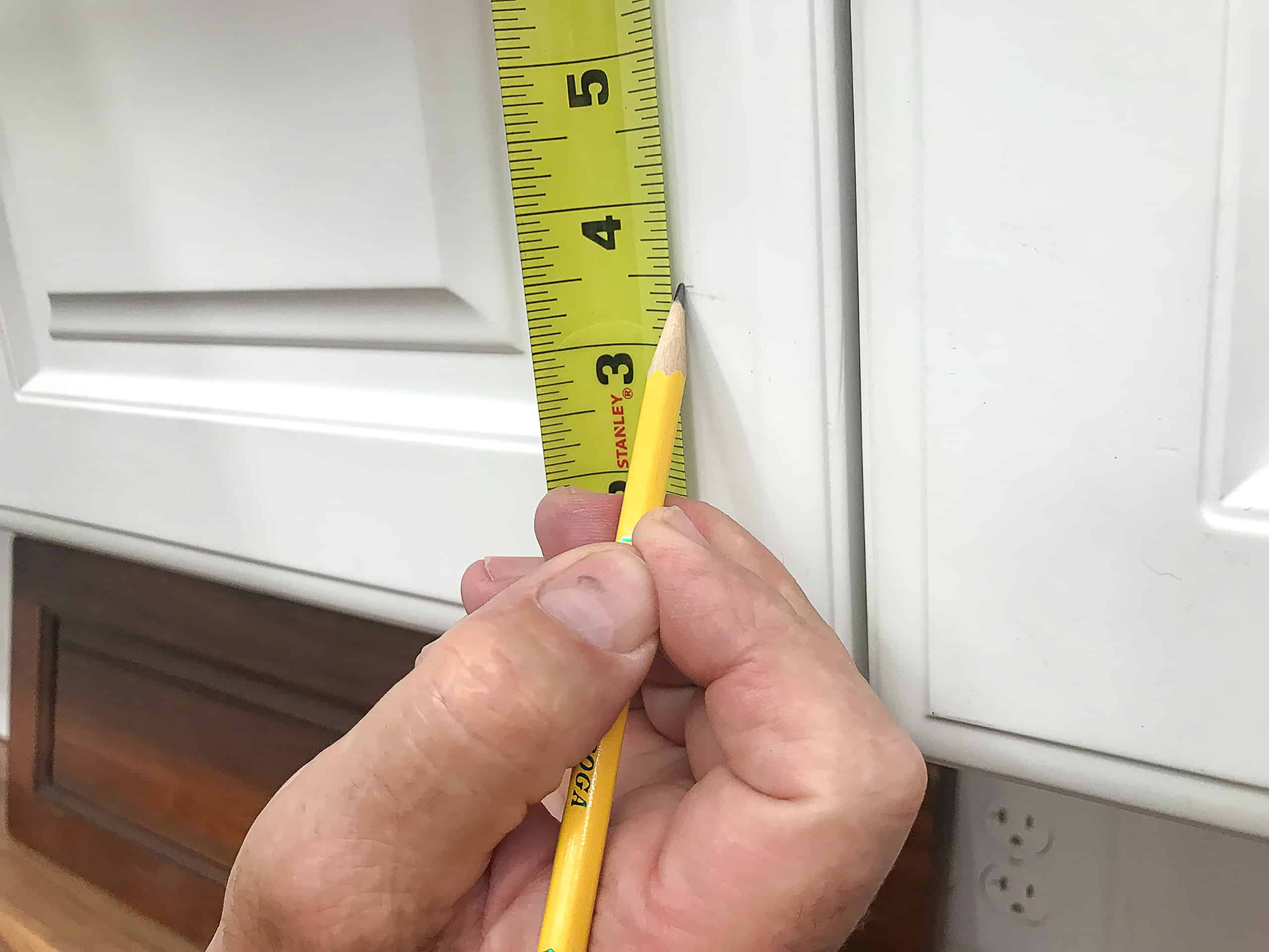 Tape measure marking white cabinet door panel