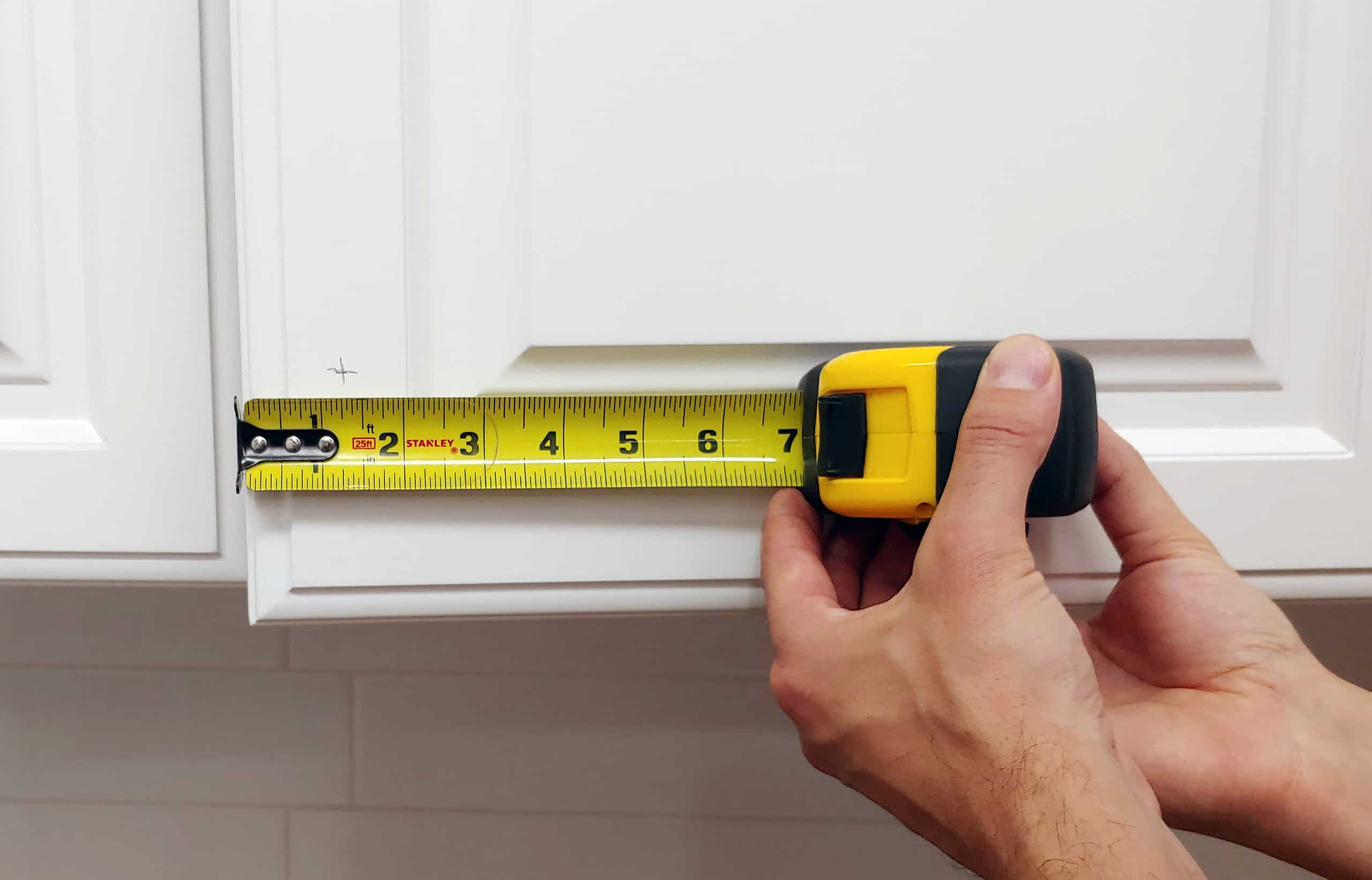 Tape measure marking white cabinet door from side